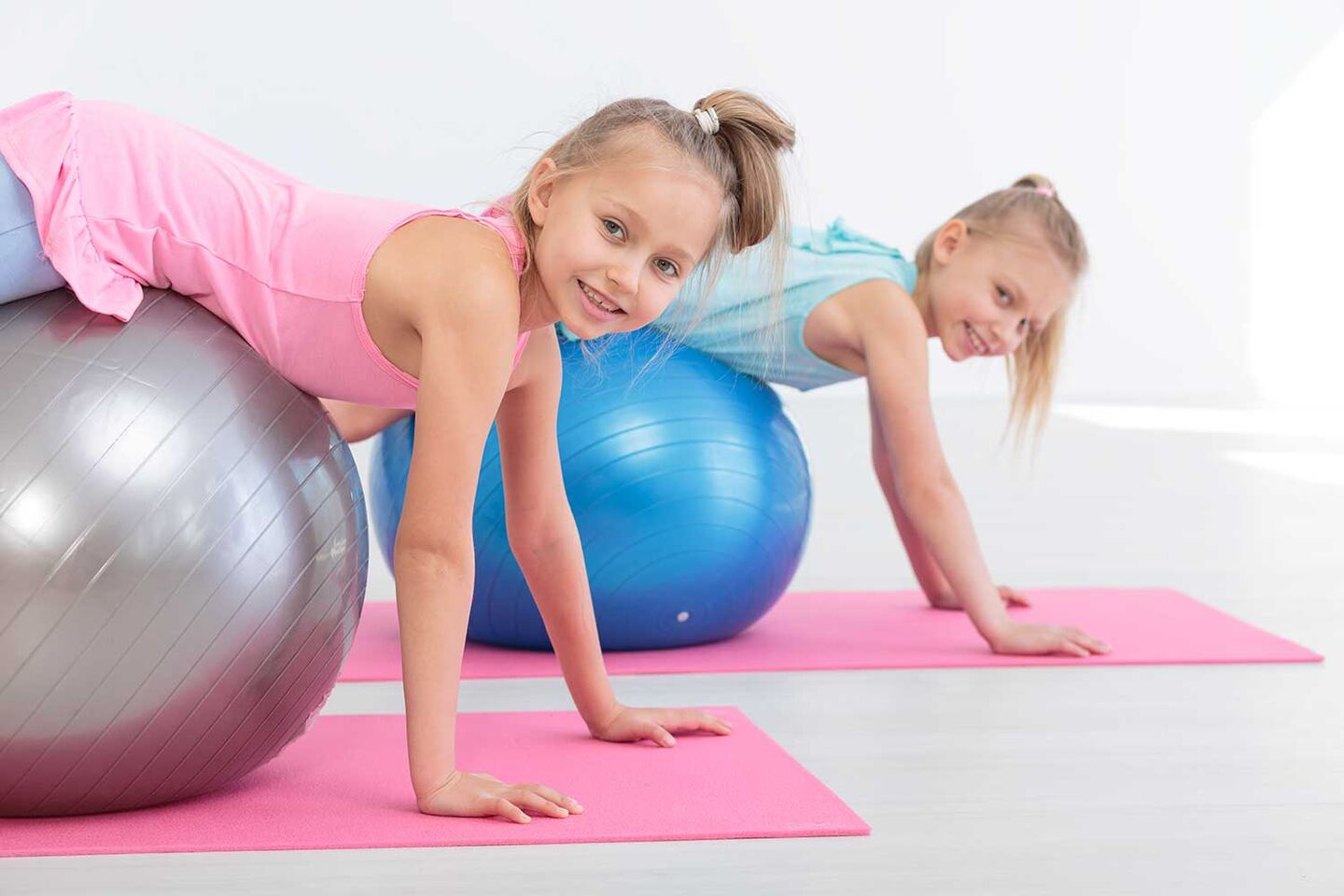 zwei kleine Kinder die sich mit dem Bauch über einen Gymnastikball rollen
