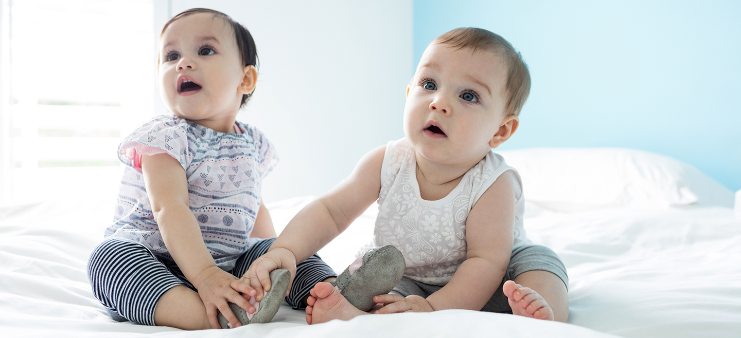 Zwei niedliche Kleinkinder auf einem Bett sitzend